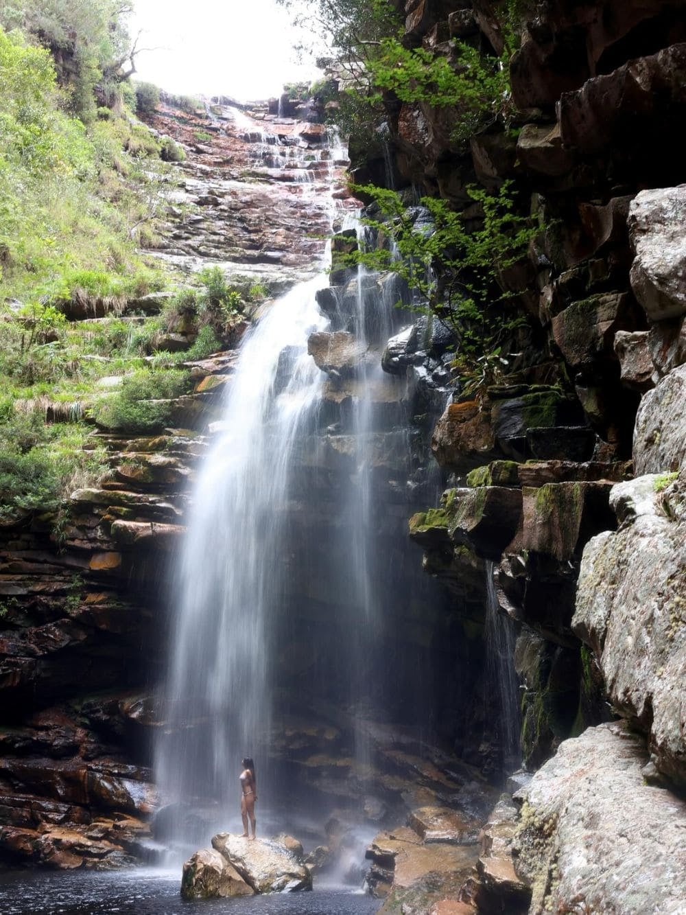 A person standing on a rock at the foot of a tall waterfall in Vale do Pati, Chapada Diamantina, Brazil. A person standing on a rock at the foot of a tall waterfall in Vale do Pati, Chapada Diamantina, Brazil.