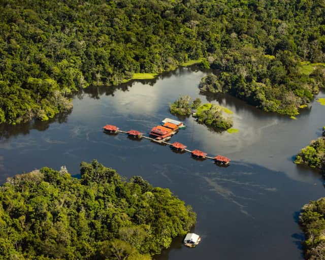 Aerial view of Uakari Floating Lodge, its red-roofed cabins lined along a walkway on the lake inside the Mamirauá Reserve Aerial view of Uakari Floating Lodge, its red-roofed cabins lined along a walkway on the lake inside the Mamirauá Reserve